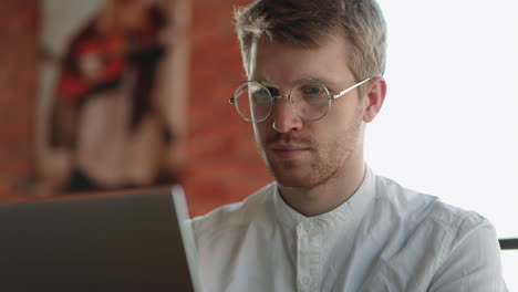 handsome-european-man-with-glasses-is-working-with-laptop-in-cafe-freelancer-is-surfing-internet-for-looking-information